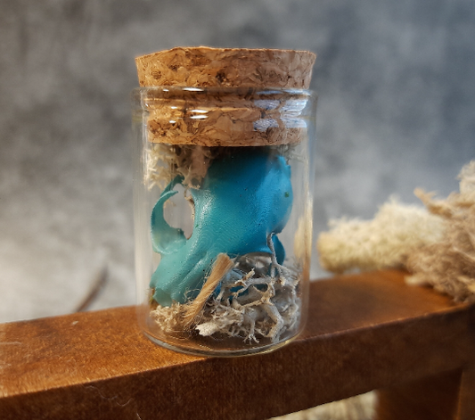 Mini cat skull turquoise in a glass with moss and bark